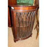 A REPRODUCTION MAHOGANY BOW FRONT CORNER UNIT with fancy bar glazed single door, supported on