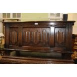 A REPRODUCTION OAK FINISHED SMALL SIZED COFFER, with lift-up lid and linen fold carved panelled