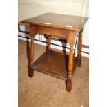 AN OAK SQUARE TOPPED COFFEE TABLE on turned and block legs, united by a plank undertier