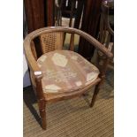 AN OAK FRAMED BERGERE BACKED HORSESHOE ARMCHAIR with associated seat pad, supported on part reeded