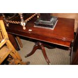 A REPRODUCTION MAHOGANY FOLDOVER TABLE supported on turned column and four outswept legs with