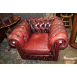 A DISTRESSED BURGUNDY LEATHER PART BUTTONED CHESTERFIELD CLUB ARMCHAIR