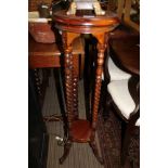 A MAHOGANY FINISHED CIRCULAR TOPPED JARDINERE STAND supported on four barley twist upright