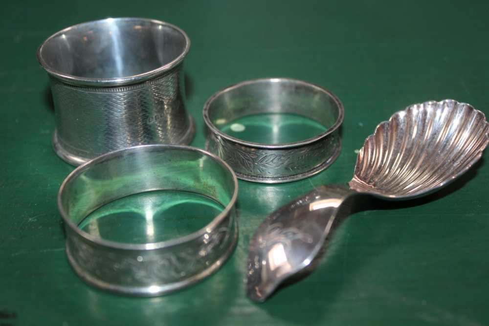 THREE HALLMARKED NAPKIN RINGS together with a silver scalloped bowl, tea caddy spoon