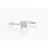 A hallmarked 18ct white gold diamond solitaire ring, set with an emerald cut diamond, measuring