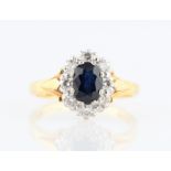 A hallmarked 18ct yellow gold sapphire and diamond cluster ring, set with an oval cut sapphire,