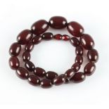 A string of red plastic beads, comprising 27 graduated oval red plastic beads with faceted red