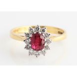 An 18ct yellow gold ruby and diamond cluster ring, set with a central oval cut ruby measuring