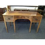 A mahogany three drawer sideboard sitting on square tapering legs.