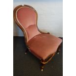 A pink upholstered spoon back nursing chair.