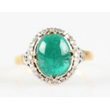 An emerald and diamond cluster ring, set with a central oval emerald cabochon, measuring approx.