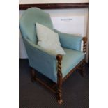 A blue upholstered arm chair with barley twist columns to arms.