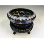 A cloisonné dragon design bowl on wood carved oriental base.