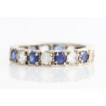 A sapphire and colourless paste full eternity ring, set with alternating round cut sapphires and