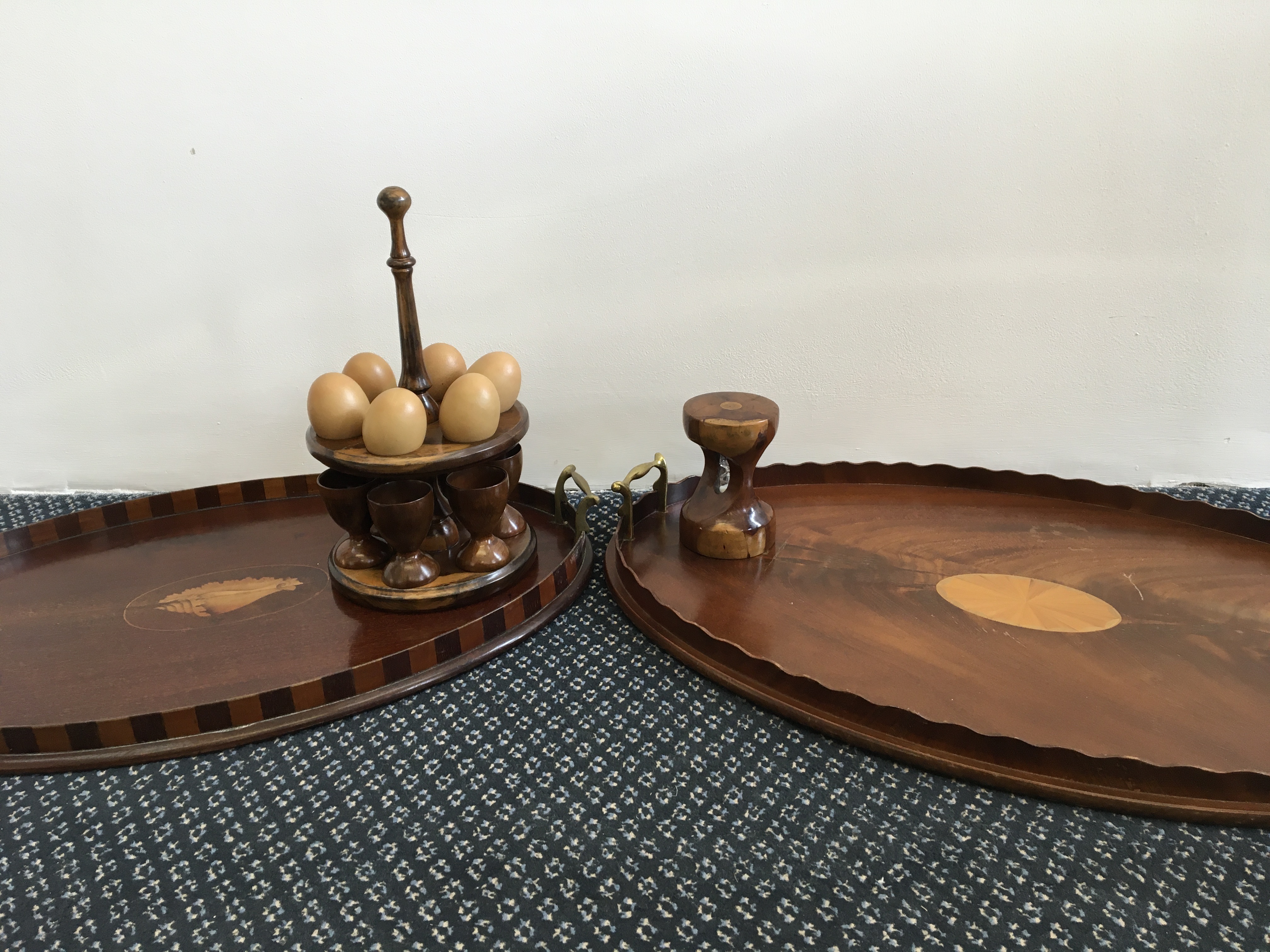 Two mahogany trays with inlay designs, together with a timer and an egg stand, with six cups and six