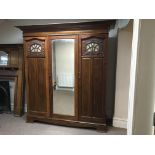 A mahogany triple door wardrobe with Art Nouveau design and glass panels and central mirror door.