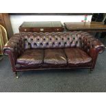 An ox blood three-seater leather Chesterfield style sofa with button back.