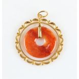 An orange jadeite jade pi disc pendant, with surrounding unmarked yellow metal open metalwork frame,