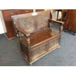 An oak carved panelled monk's bench, 74cm x 99cm x 46cm.