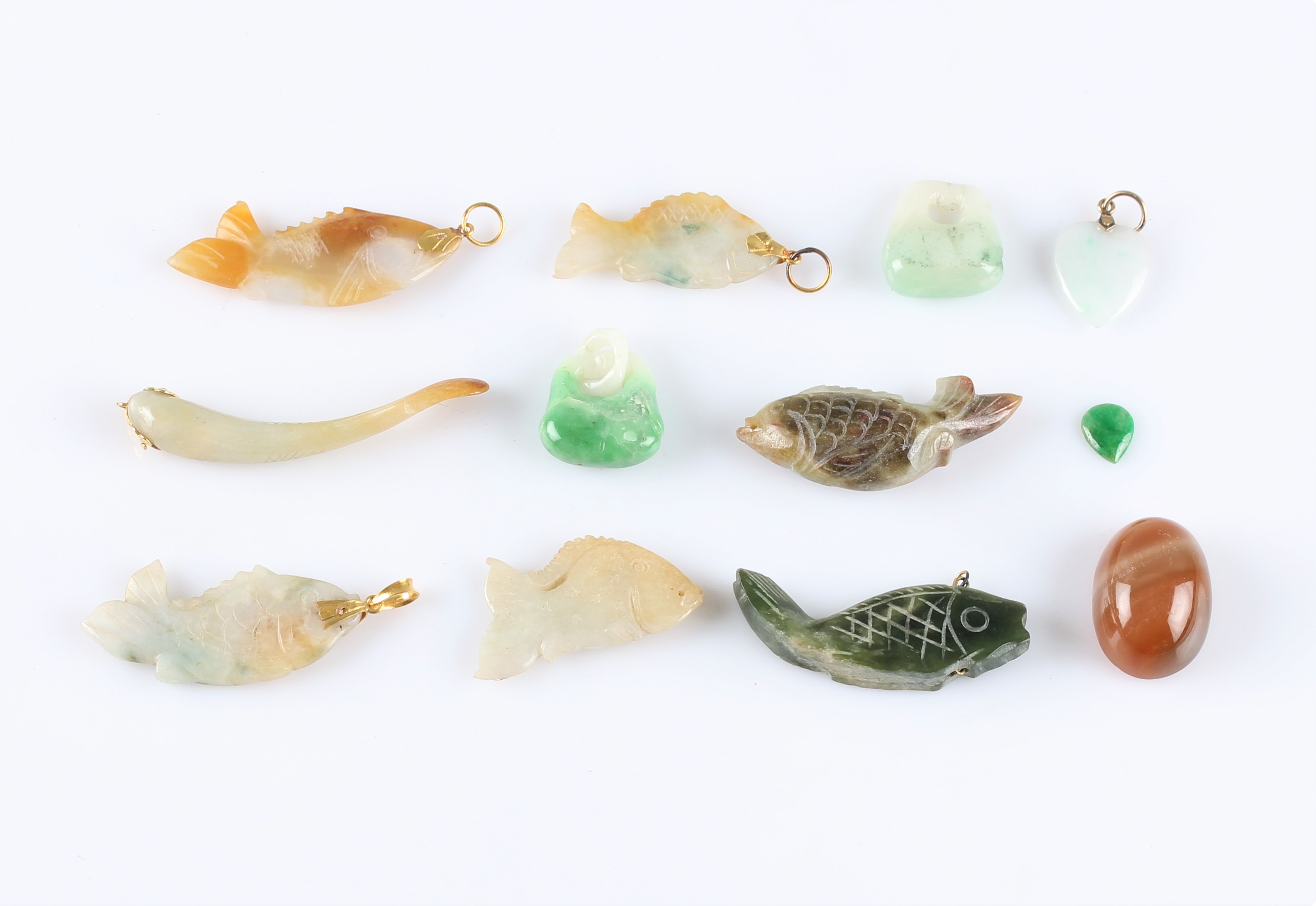 A collection of carved hardstone pendants, to include a heart, seven fish and two others, along with