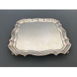 A silver Mappin & Webb salver of square form shaped edge on four squat feet, hallmarked London 1914,