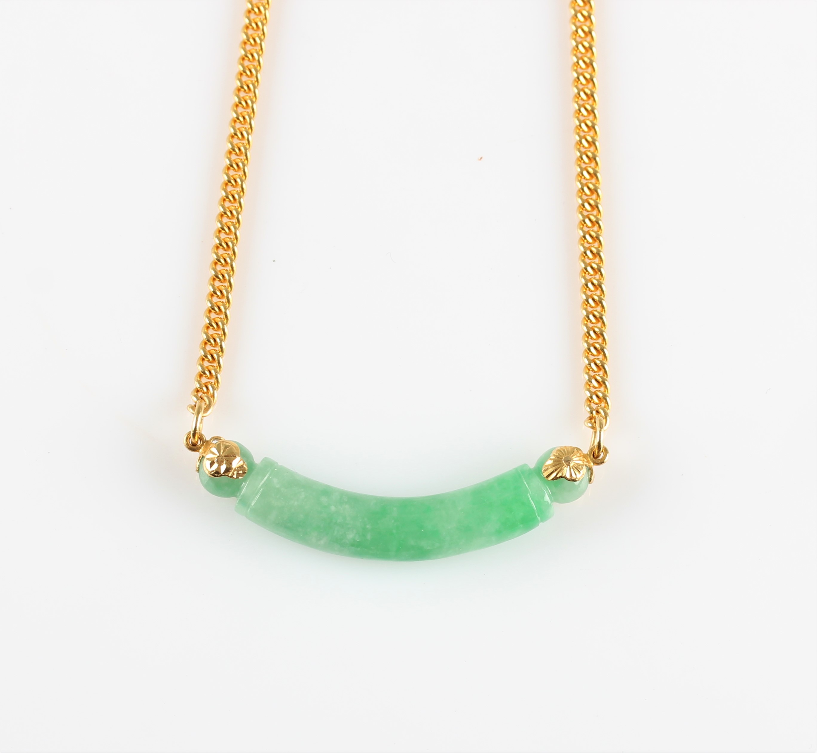 A green jade necklace, comprising a curved piece of carved jade attached to a belcher link chain,