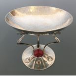 A silver Arts & Crafts tazza, the raised beaten bowl on three whiplash curve shaped supports and