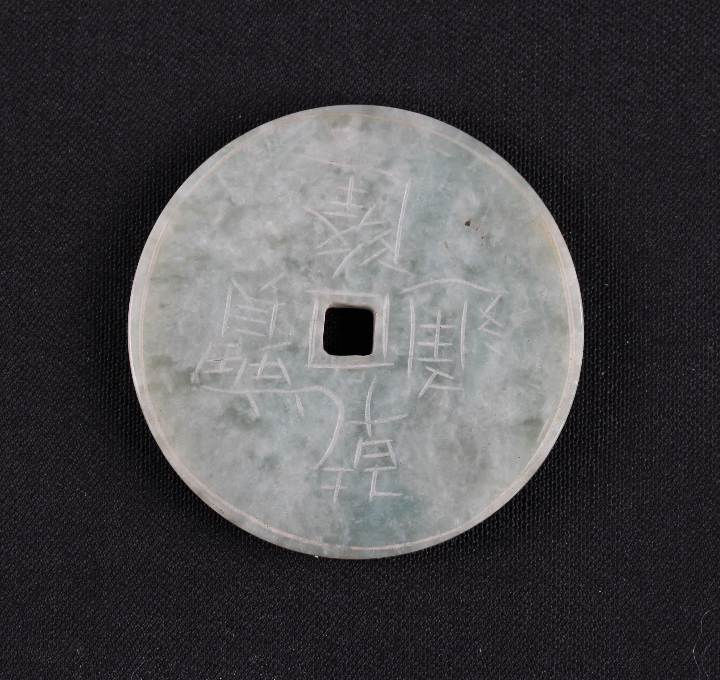 A green Oriental hardstone disc, engraved with Oriental character marks, diameter approx. 5cm.