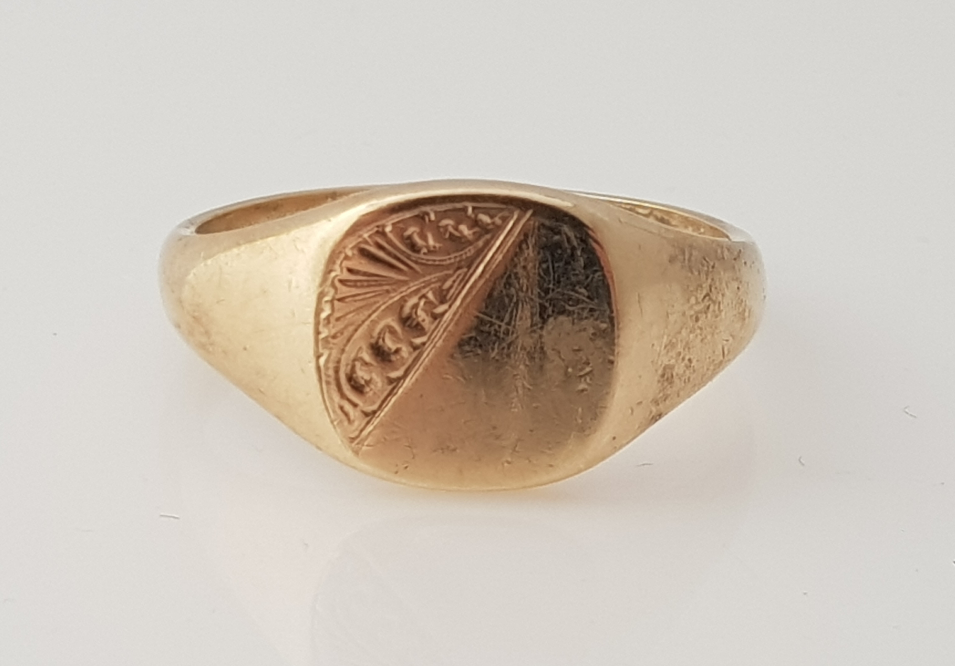 A 9ct yellow gold gents signet ring, the cushion shaped head diagonally engraved with scroll design,