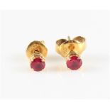A pair of ruby stud earrings, each set with a round cut ruby, measuring approx. 3mm, unmarked yellow