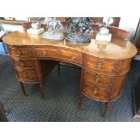 A mahogany and walnut kidney shaped seven drawer dressing table/desk. IMPORTANT: Online viewing