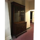 An early 19th century mahogany cupboard base glazed top bookcase with Gothic theme to glass.