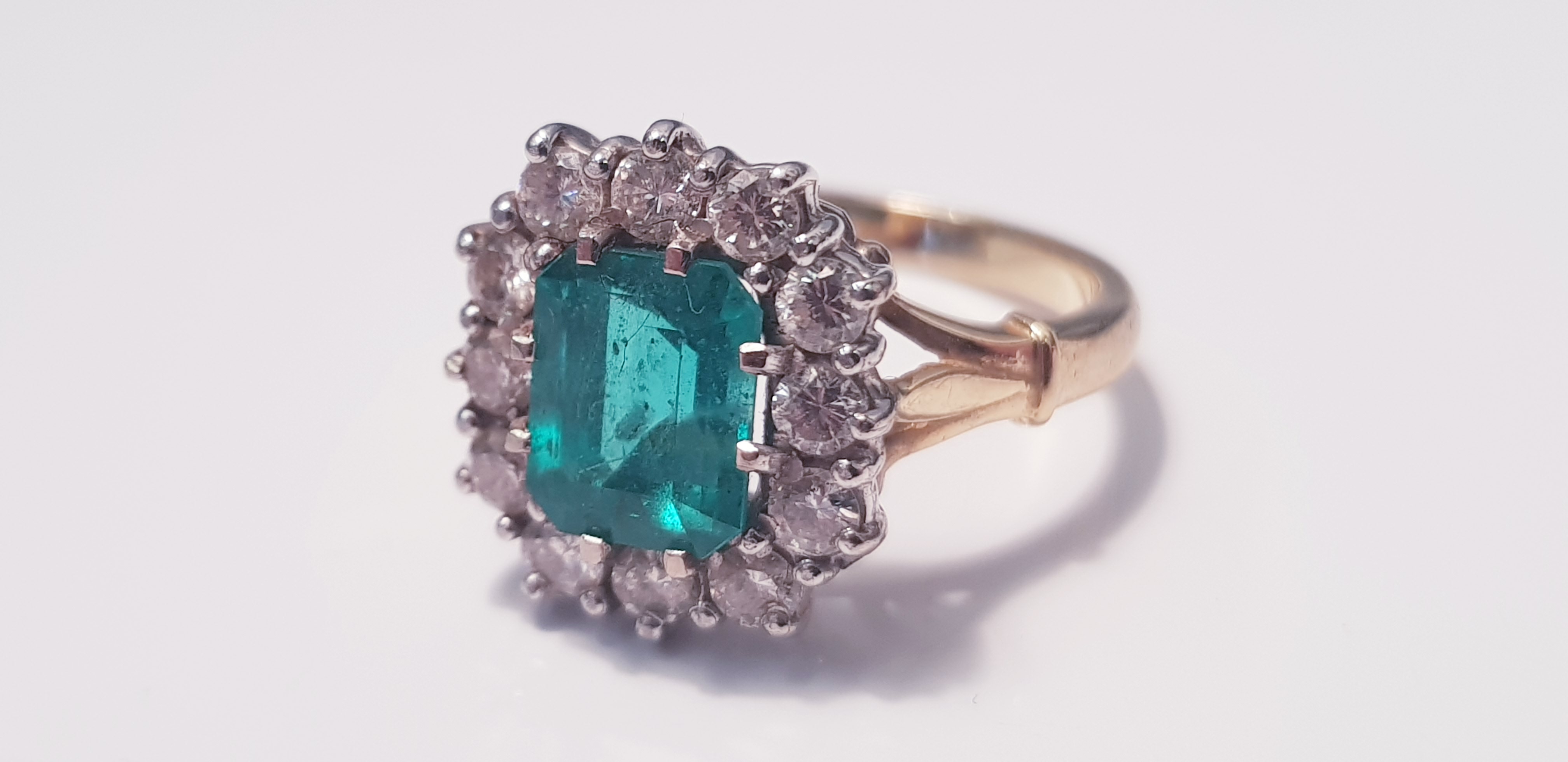 A yellow gold emerald and diamond square cluster ring, marked 750 , 12 diamonds surrounding emerald,