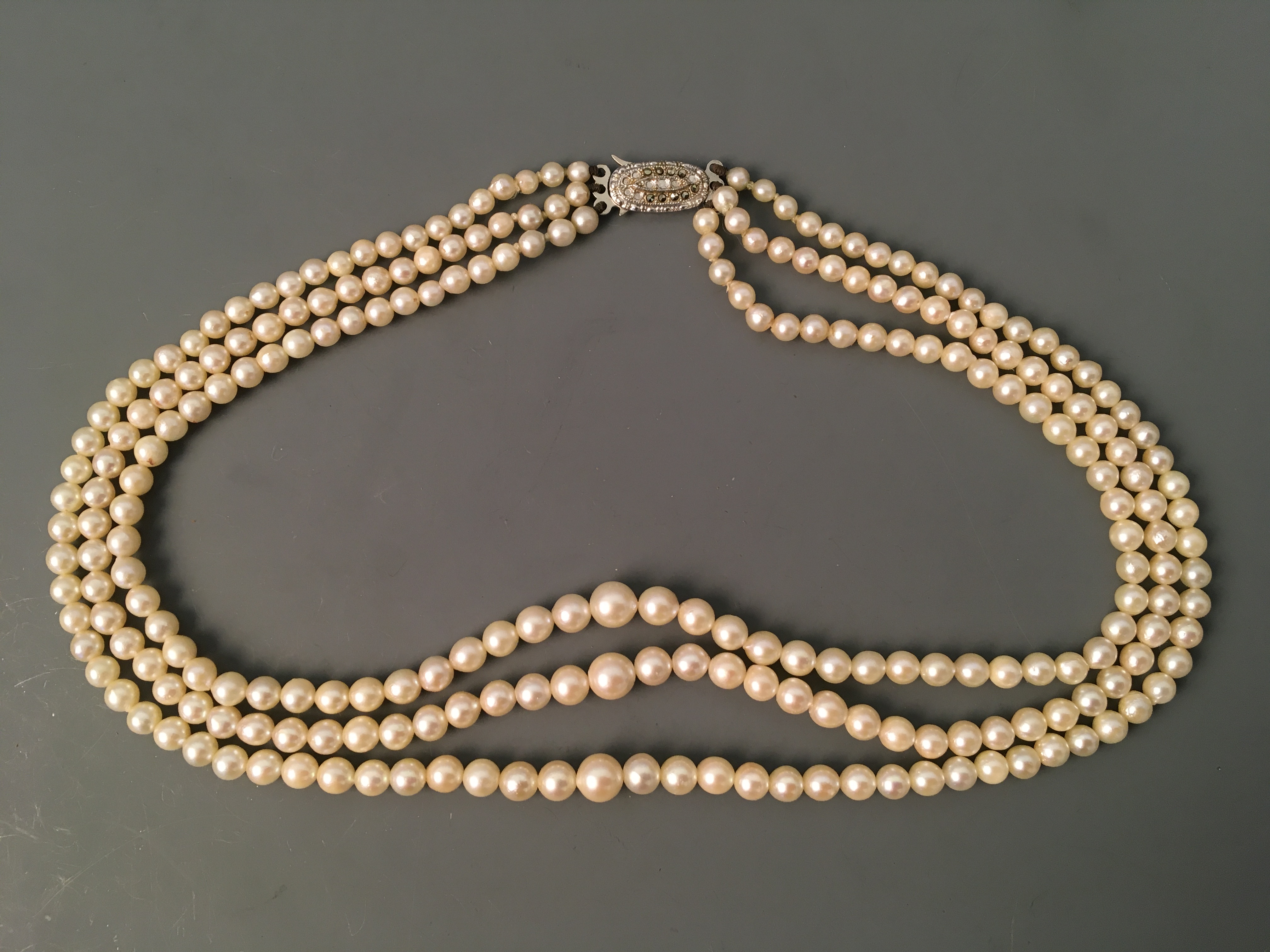 A three row string of pearls, 'Ledawn' with gem stone clasp marked sterling silver. IMPORTANT: