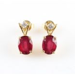 A pair of treated ruby and diamond drop stud earrings, set with an oval cut glass-filled ruby