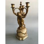 An ormolu three light candelabra with three putto on white marble base with swag detail, height