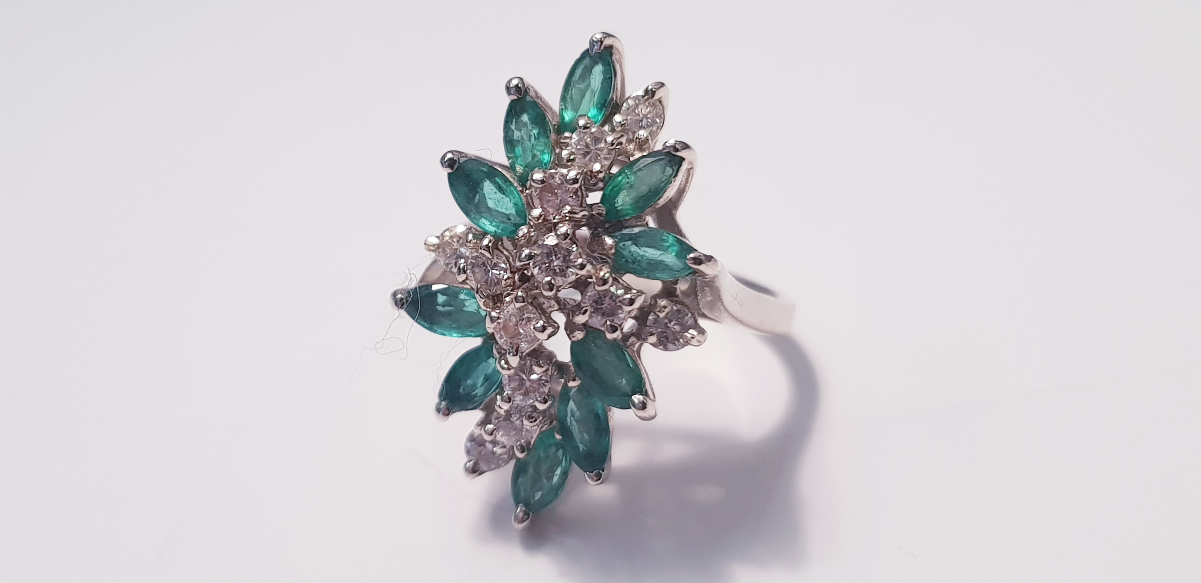 A white metal emerald and diamond dress ring, with twelve diamonds and ten emeralds, ring size L 1/