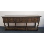 A distressed oak Jacobian style three drawer dresser base on turned and fluted columns with carved