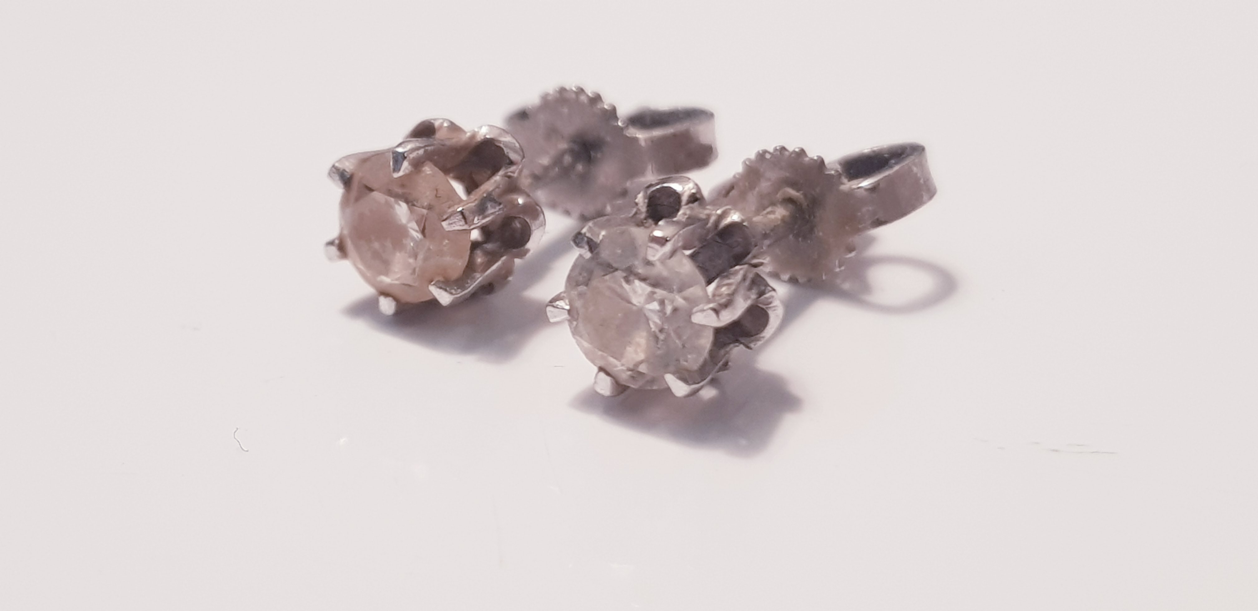 A pair of diamond stud earrings on white metal, each earring approx.0.33ct. On line viewing and