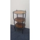 An early 19th century three tier rosewood stand on ebonised columns with pierced brass gallery