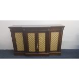 A rosewood 19th century break front four door sideboard with brass mesh and cream silk background.