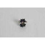 A white gold sapphire and diamond chips ring in design of a flower with petals , marked 18k, ring