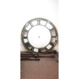 A large black and gold painted cast iron building front clock face with Roman numerals, faintly