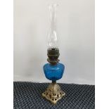 A cast iron base oil lamp with blue glass reservoir, height 54cm. IMPORTANT: Online viewing and