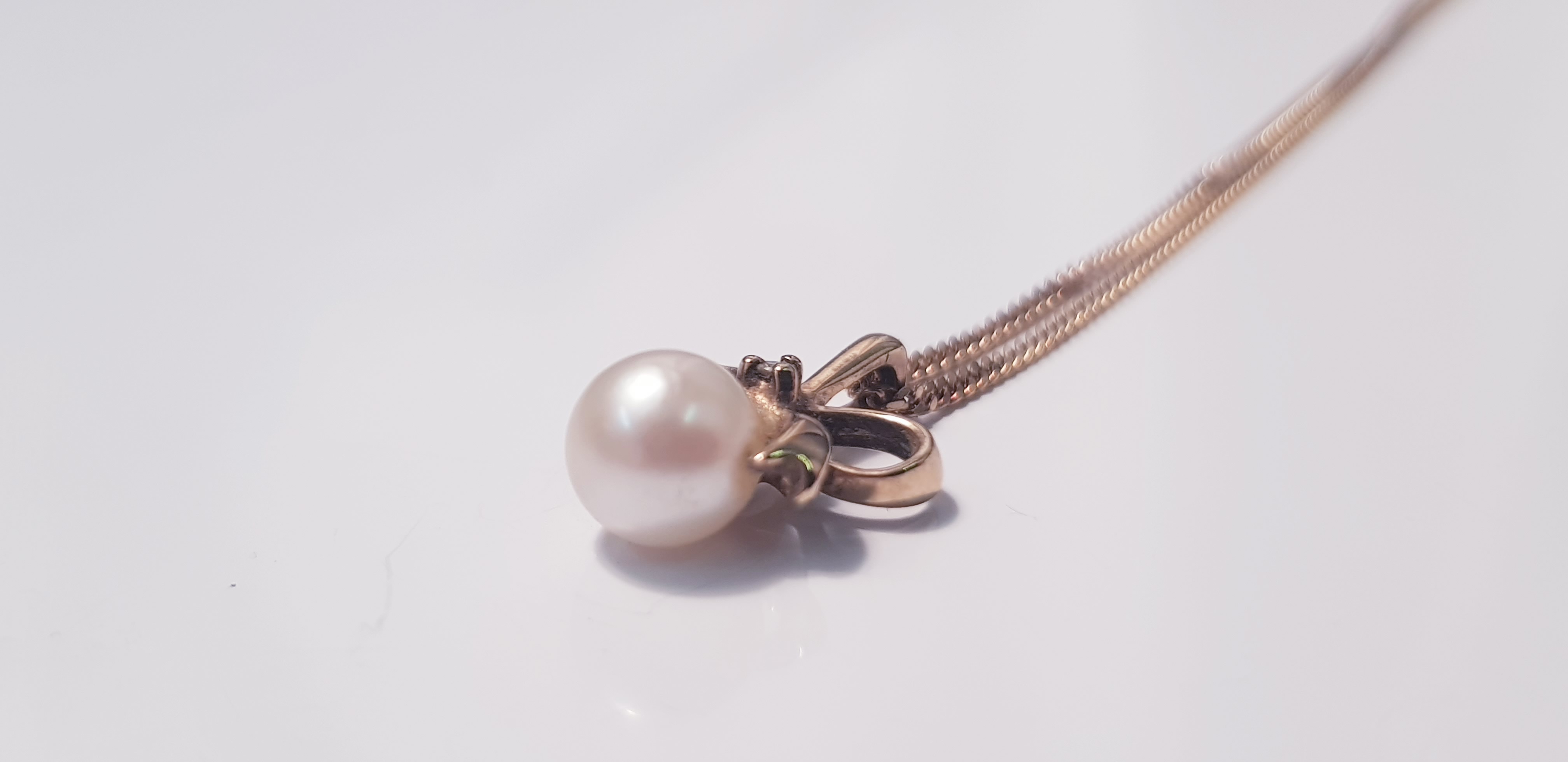 A drop pendant of a pearl and gem stone, bow design on a link chain, approx. length 18,approx.