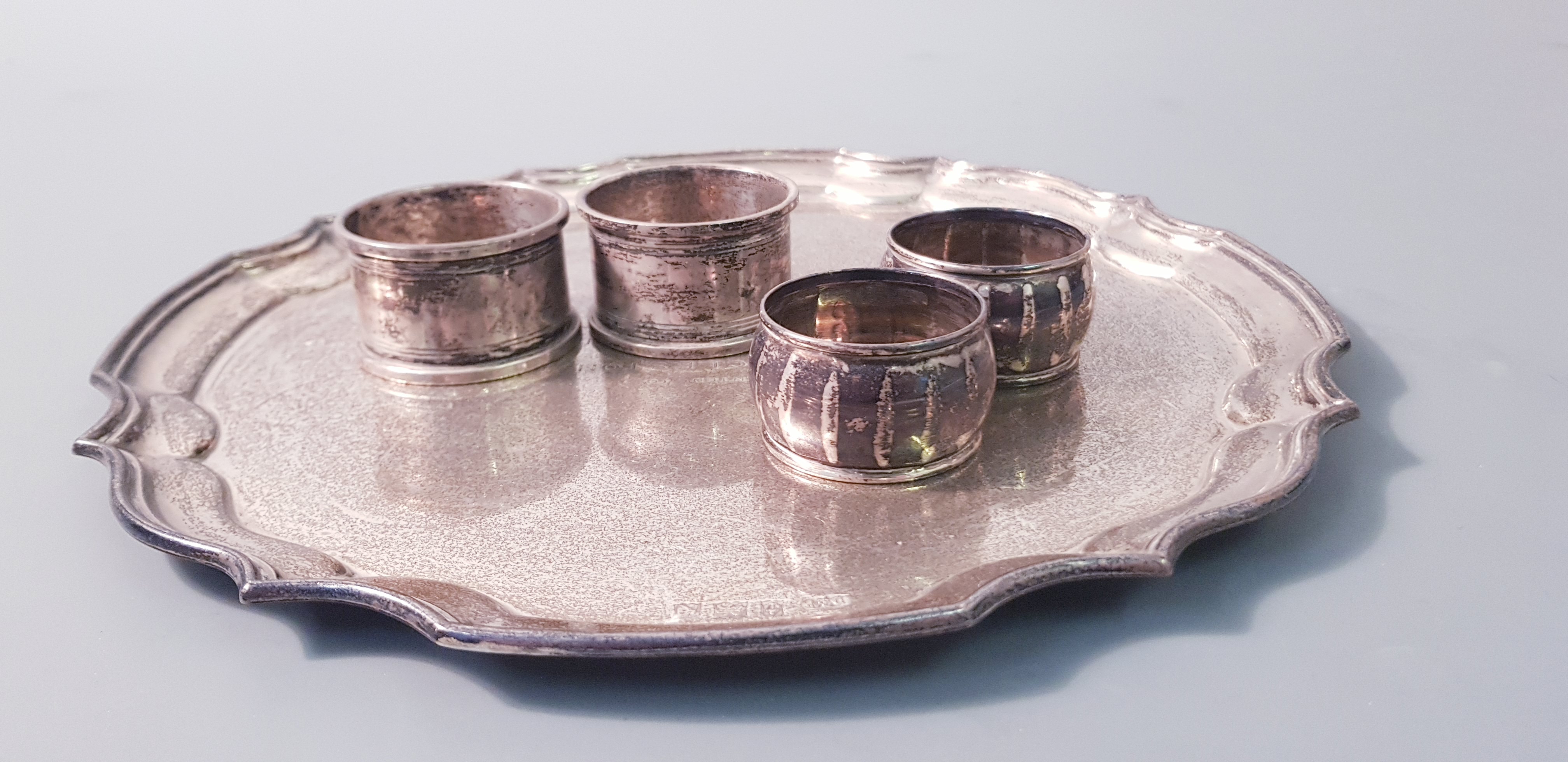 A plated ware tray, approx, width 10 with four various napkin rings, two hallmarked. Online