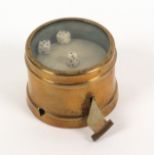 A lacquered brass novelty tape measure of circular form, the glazed top enclosing three miniature