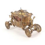 A gilt brass novelty tape measure in the form of the coronation coach, complete tape printed in ins.