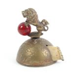 A novelty brass tape measure in the form of a half globe surmounted by a lion holding a glass