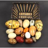 A collection of seventeen eggs in various materials, mostly wooden and of box form, three containing